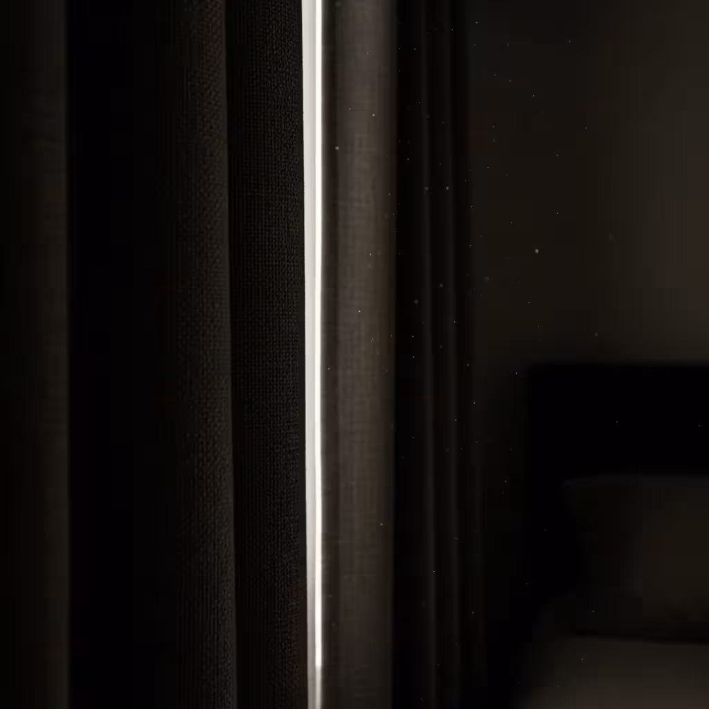 A close-up on a dark, heavy blackout curtain effectively blocking out bright daylight in a bedroom, creating a cave-like environment.
